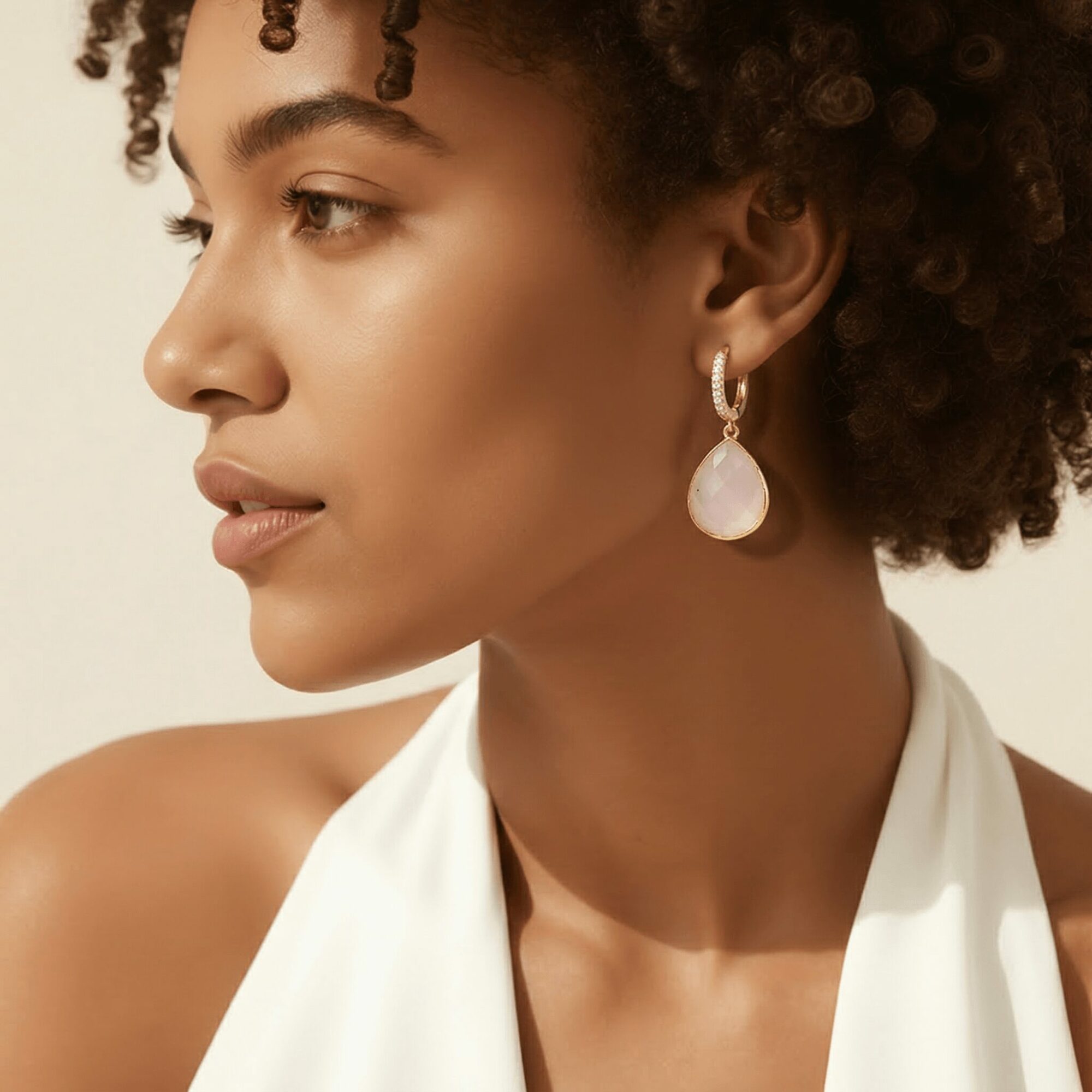 Close-up of a woman with curly hair wearing a white top and a large pearl earring.