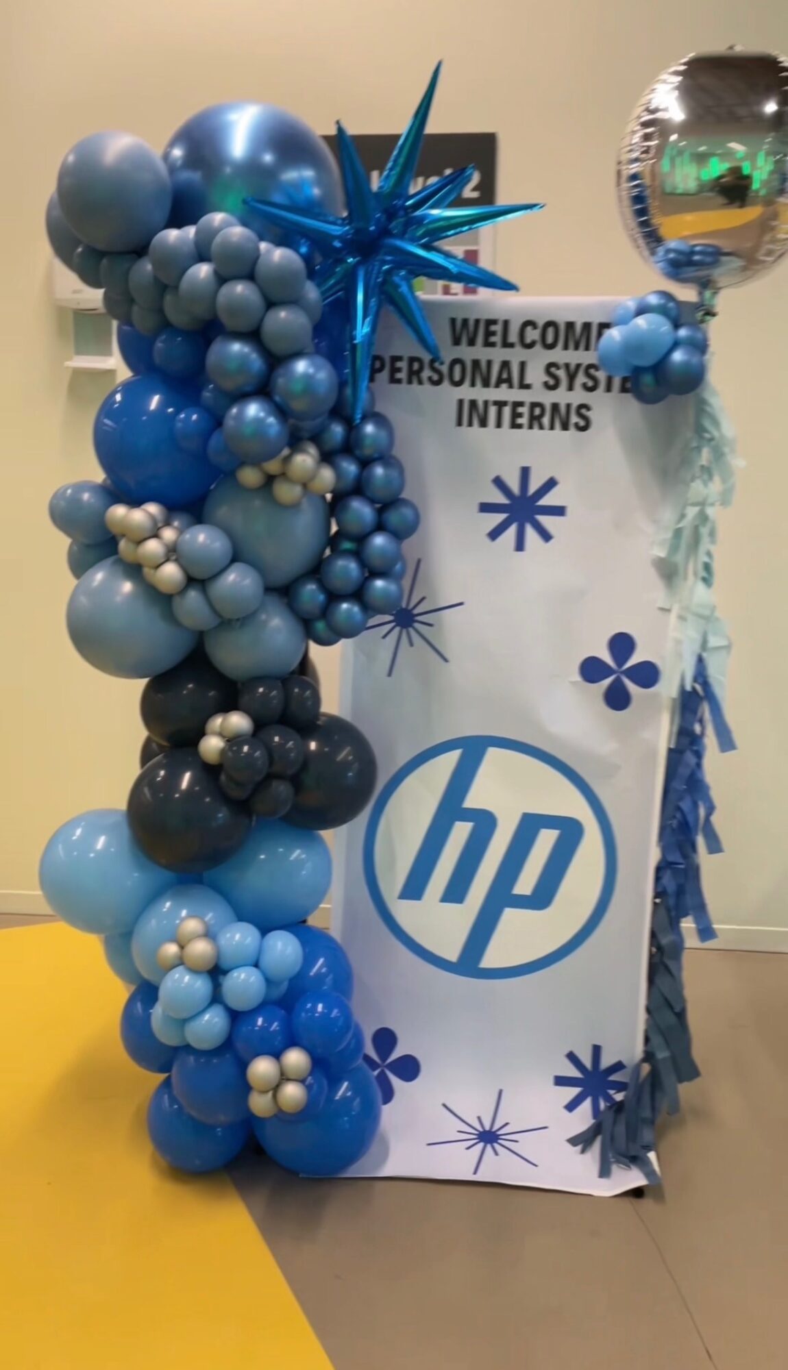 Balloon arrangement with blue, white, and black balloons next to a sign for HP interns and personal system interns.