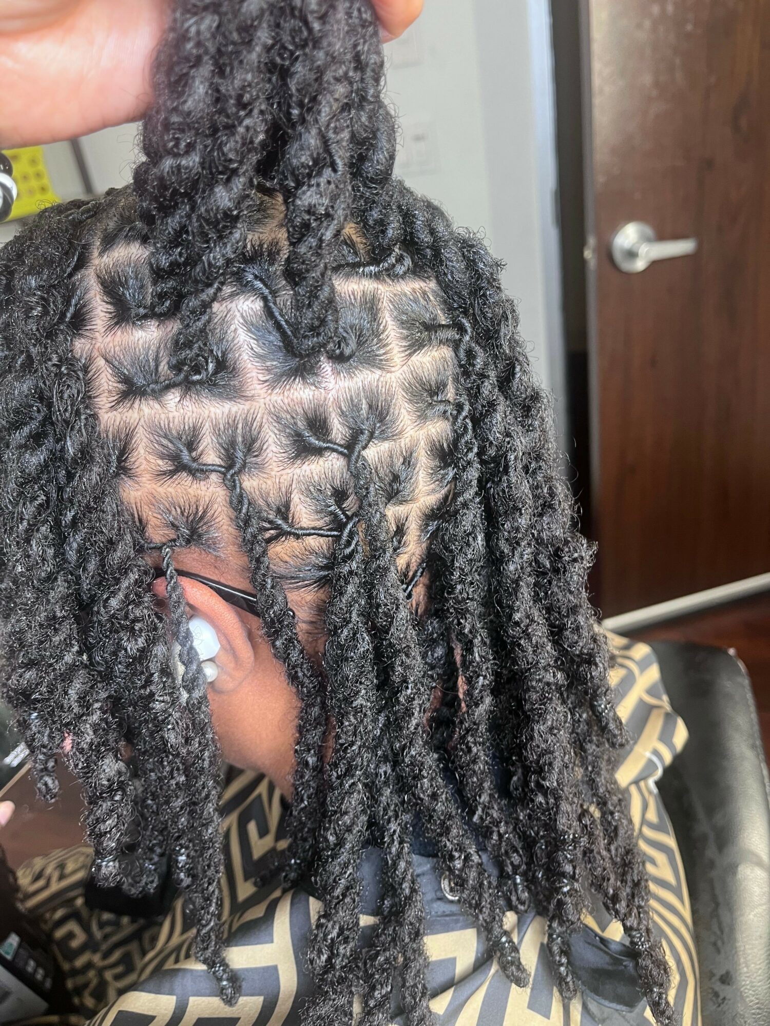 Close-up of a person's head with styled dreadlocks, showing intricate hair pattern and texture.