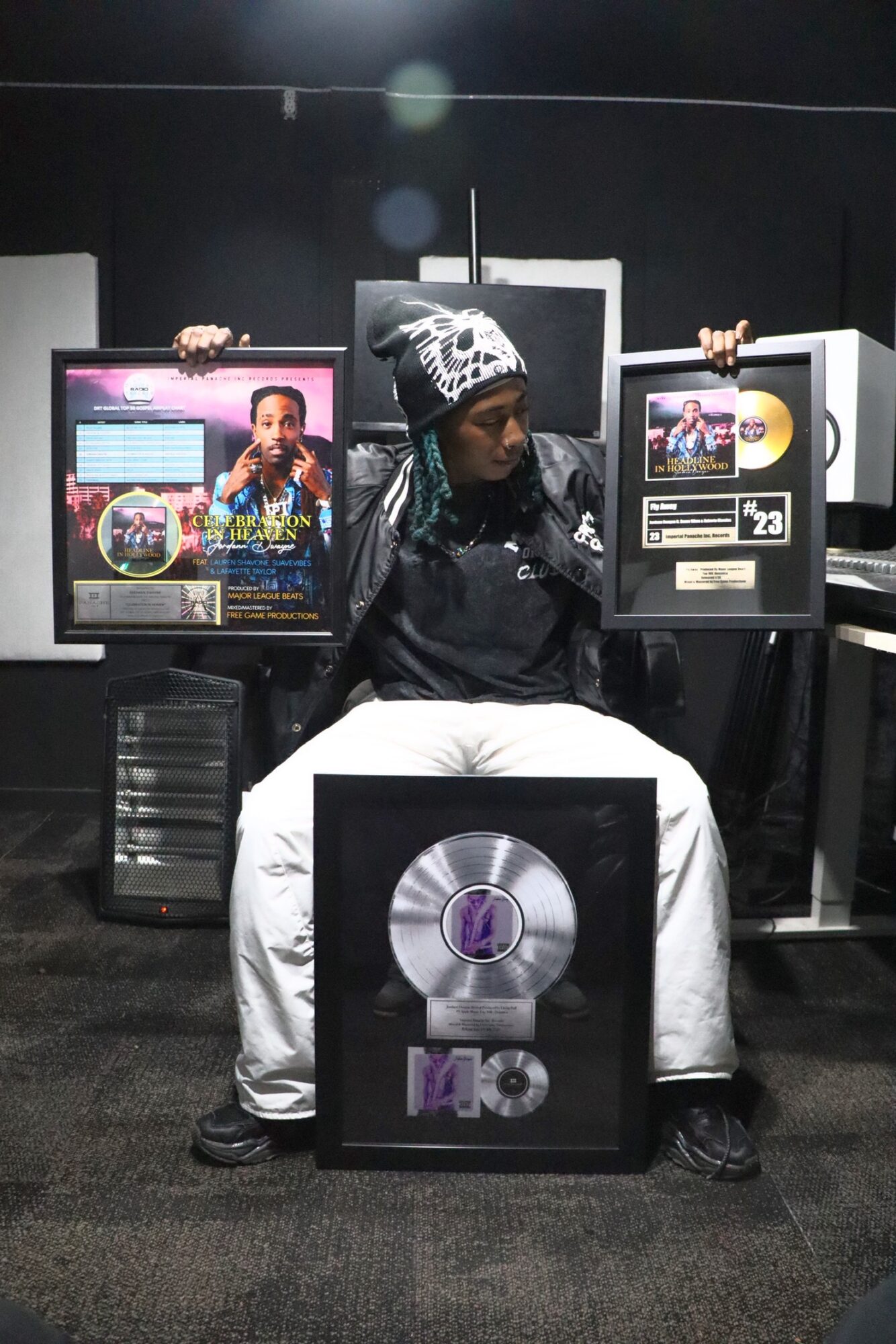 Person sitting in front of a large screen with a vinyl record display, wearing a beanie and black jacket.