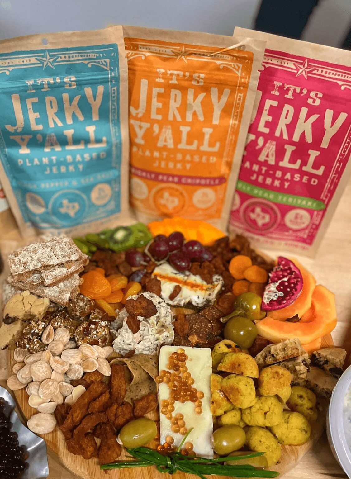 Assorted snacks and three packages of Jerky Y'all flavored jerky in blue, orange, and pink packaging.