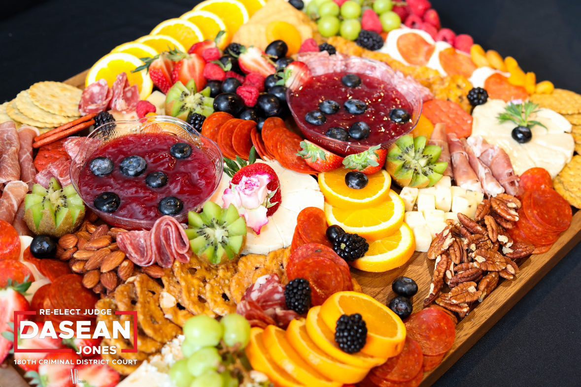 Assorted fresh fruits and nuts on a tray, including strawberries, grapes, kiwi, pineapple, and almonds.