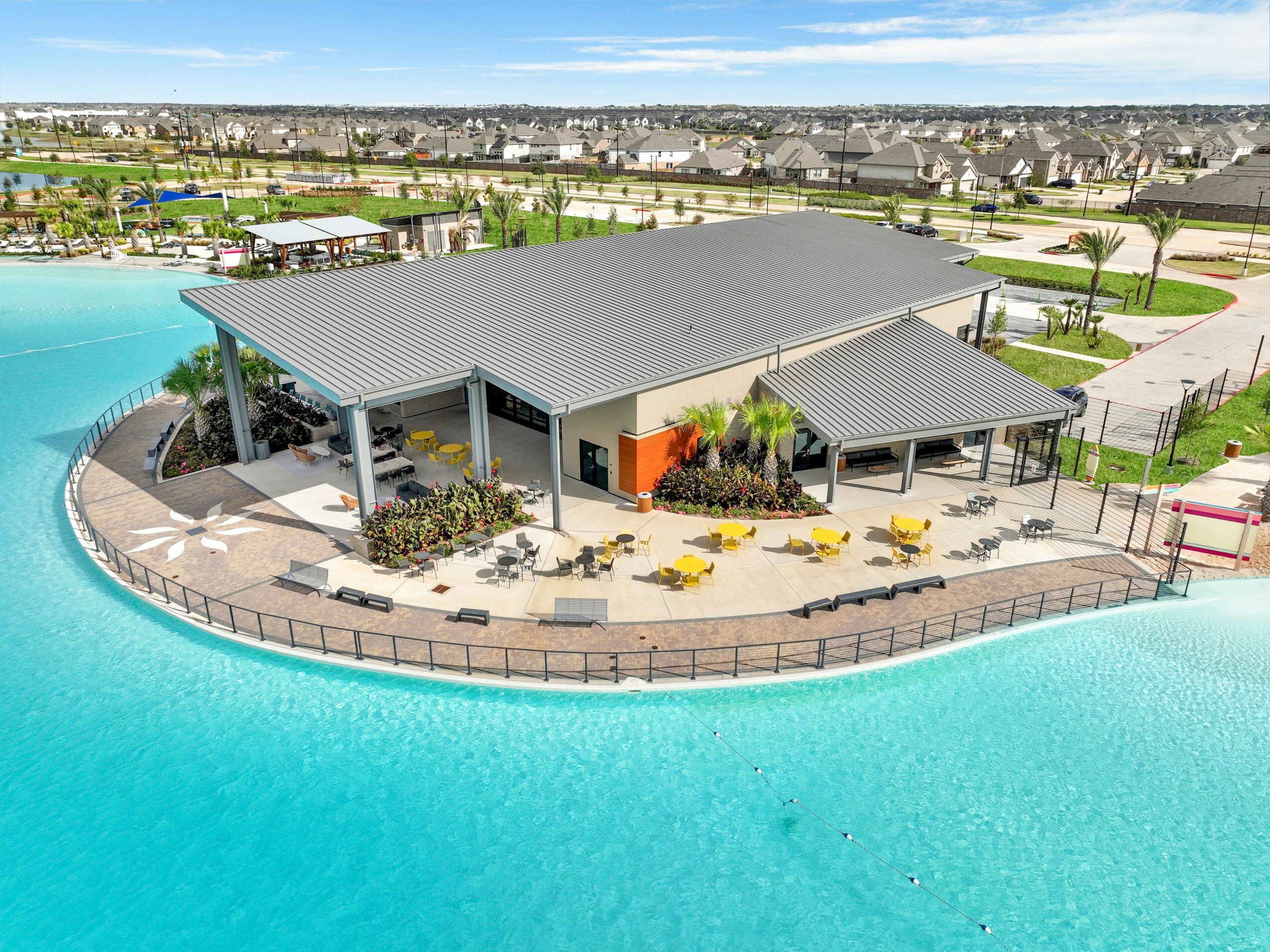 Building with a large roof, surrounded by water, with outdoor seating and landscaping.