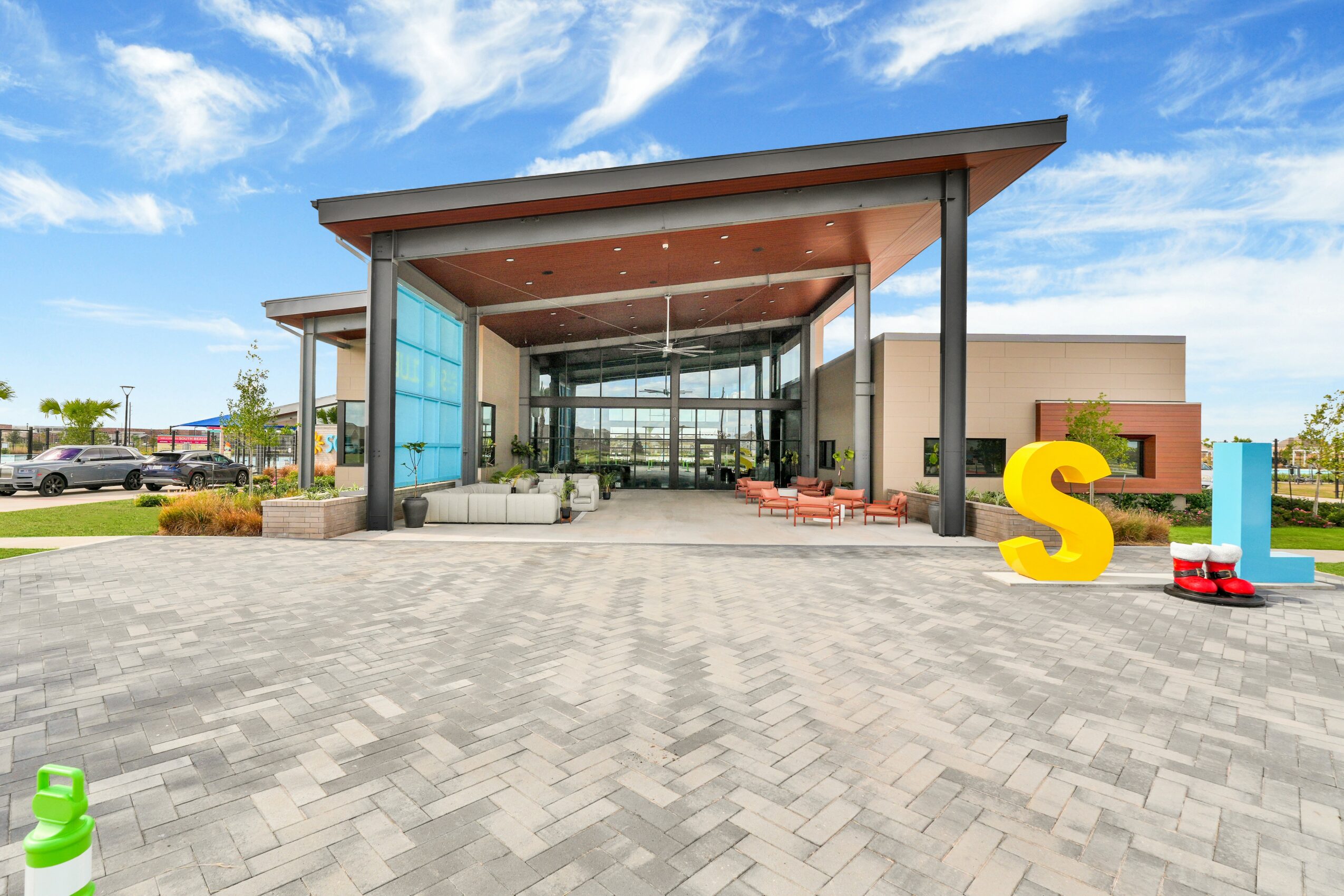 Modern building entrance with large glass doors, a covered walkway, and colorful decorative letters outside.