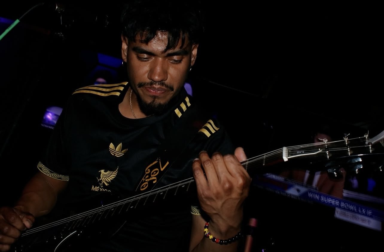 Person playing guitar in a dark environment with focused expression.