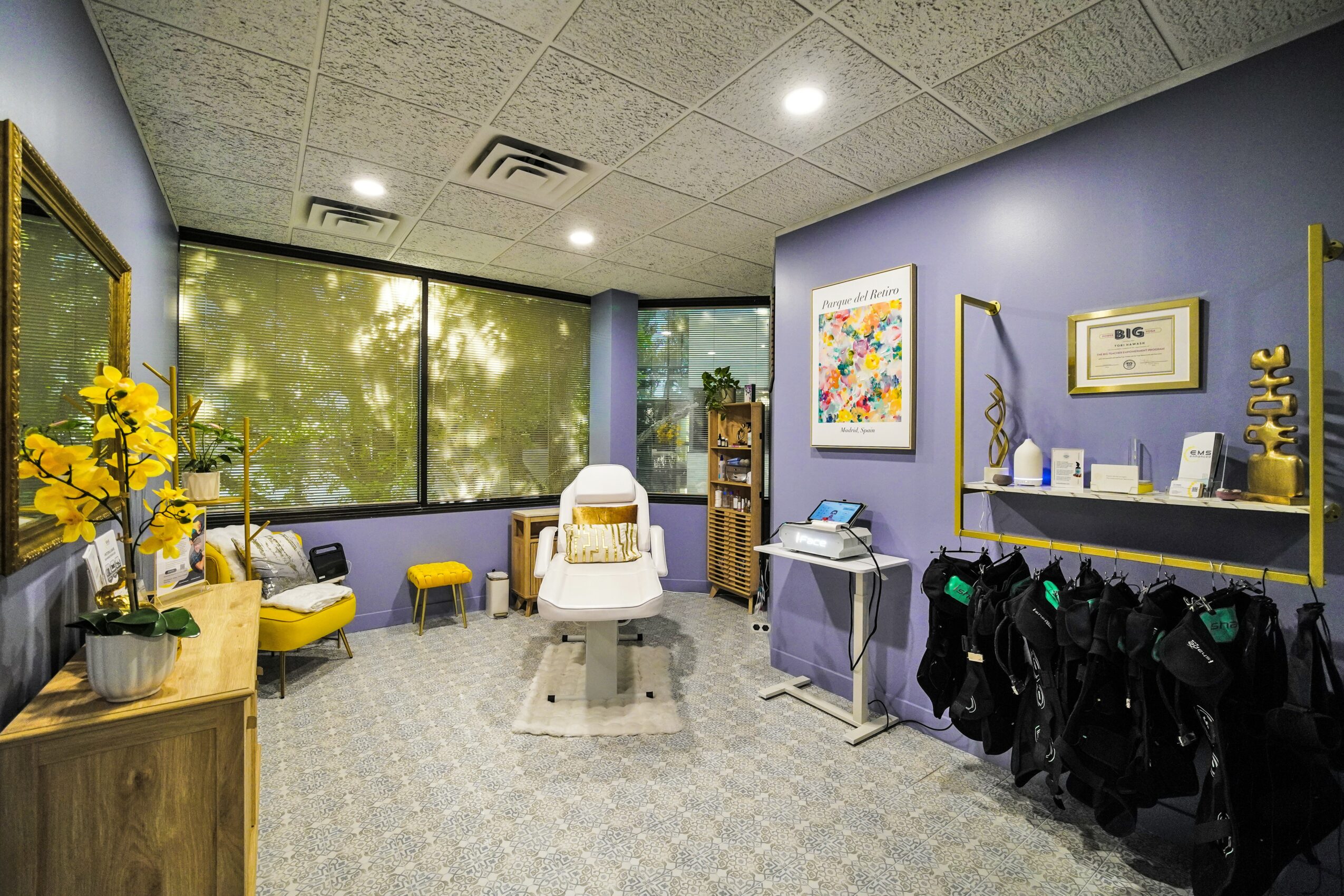 Room with purple and yellow decor, chairs, artwork, and a window with trees outside.