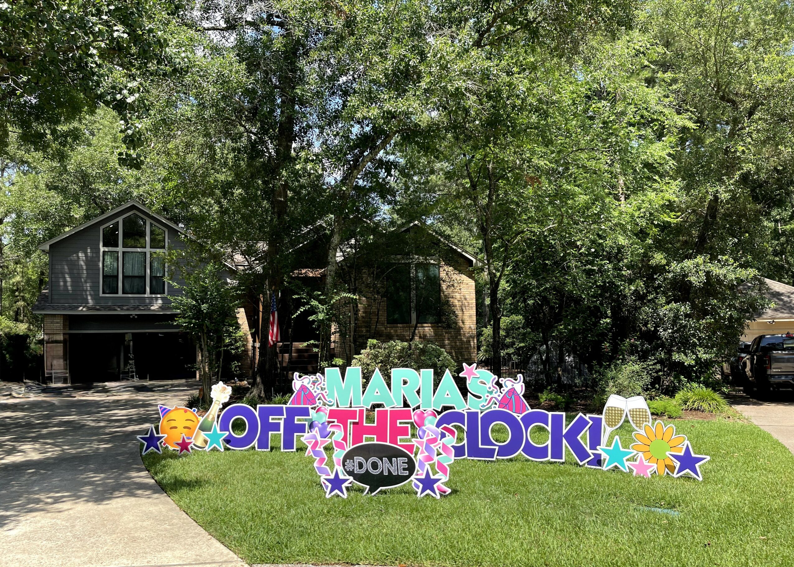 Decorative sign with colorful letters and stars in front of a house and trees, celebrating a birthday.