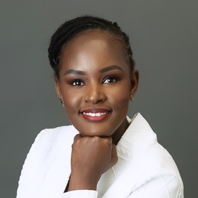 Portrait of a woman with braided hair, smiling, resting her chin on her hand, wearing a white top.