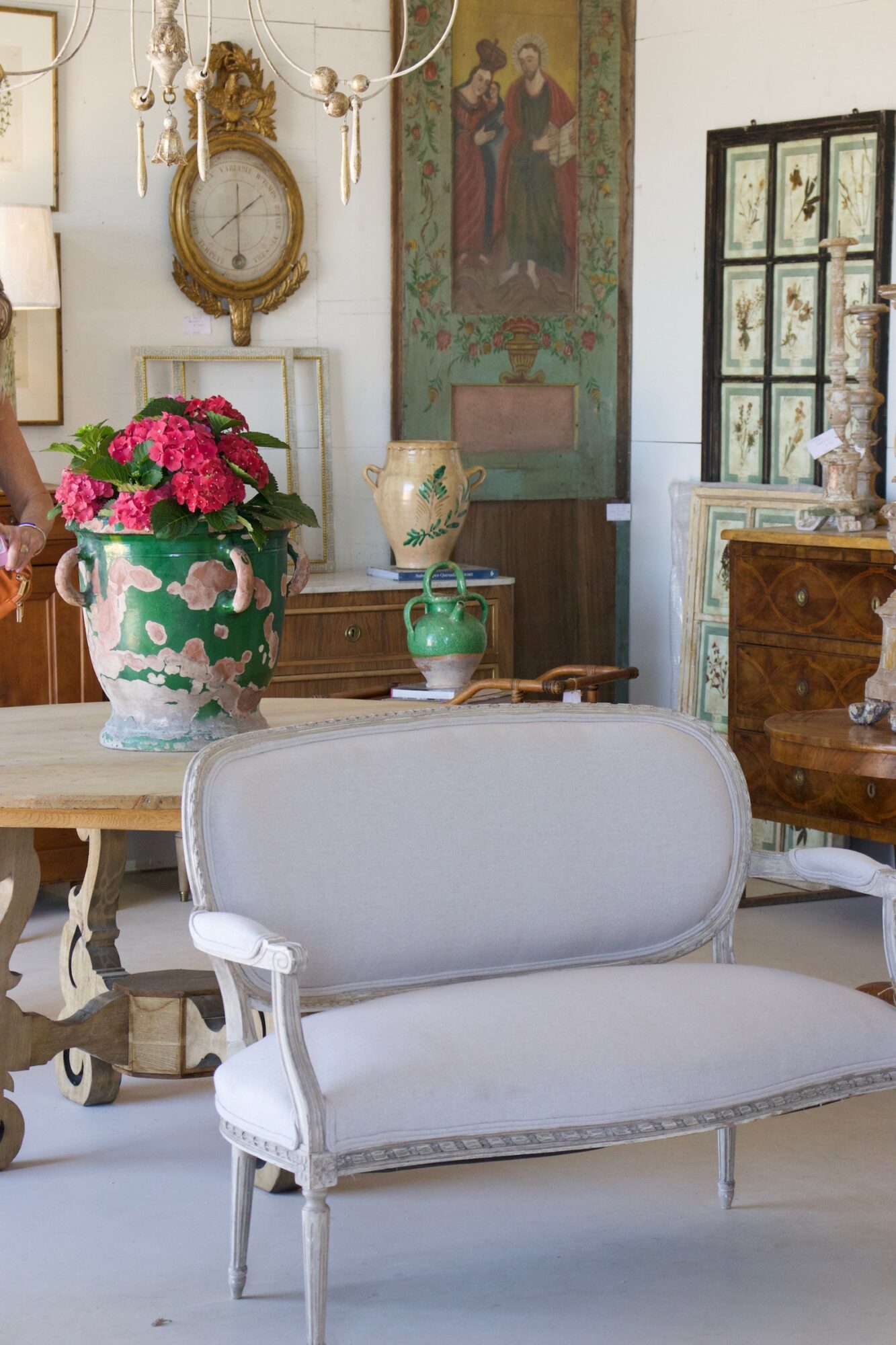 Elegant vintage living room with a white upholstered sofa, large floral vase, and antique decor elements.