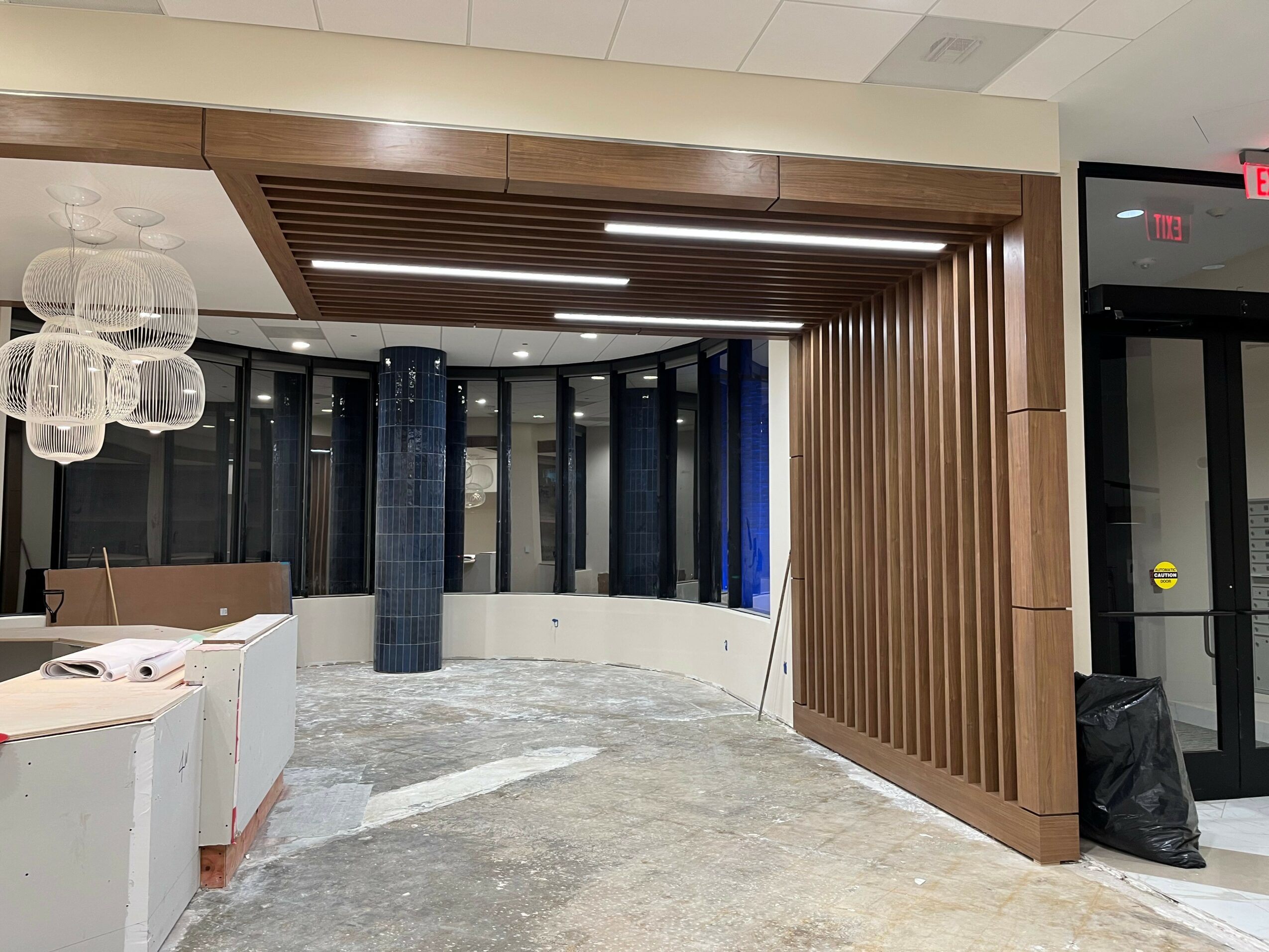 Interior space with wooden wall paneling, large windows, and construction materials on the floor.