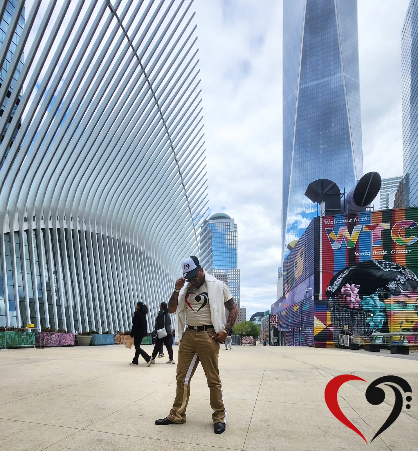 Person standing outdoors in an urban area with modern buildings and a colorful structure in the background.