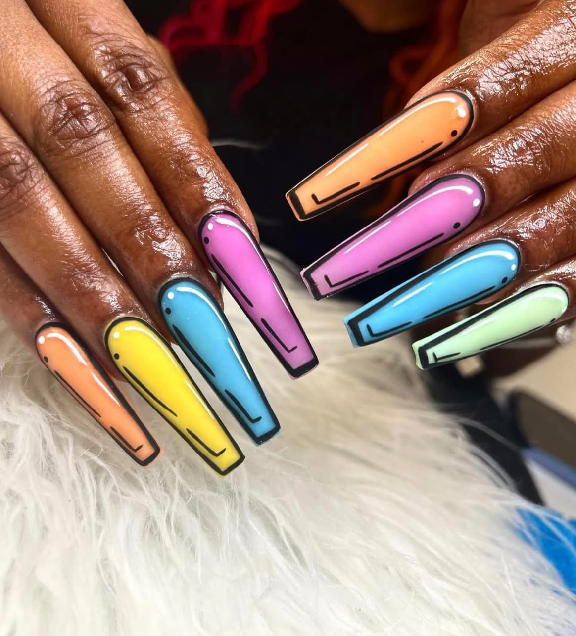 Close-up of hands with colorful, long, square-shaped nails painted in pastel shades, resting on a white furry surface.