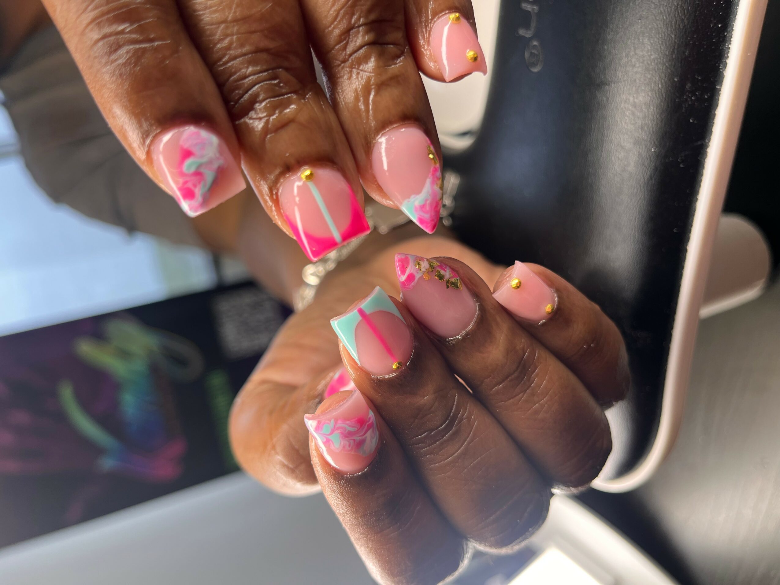 Close-up of hands with colorful, decorated nails resting on a laptop keyboard.