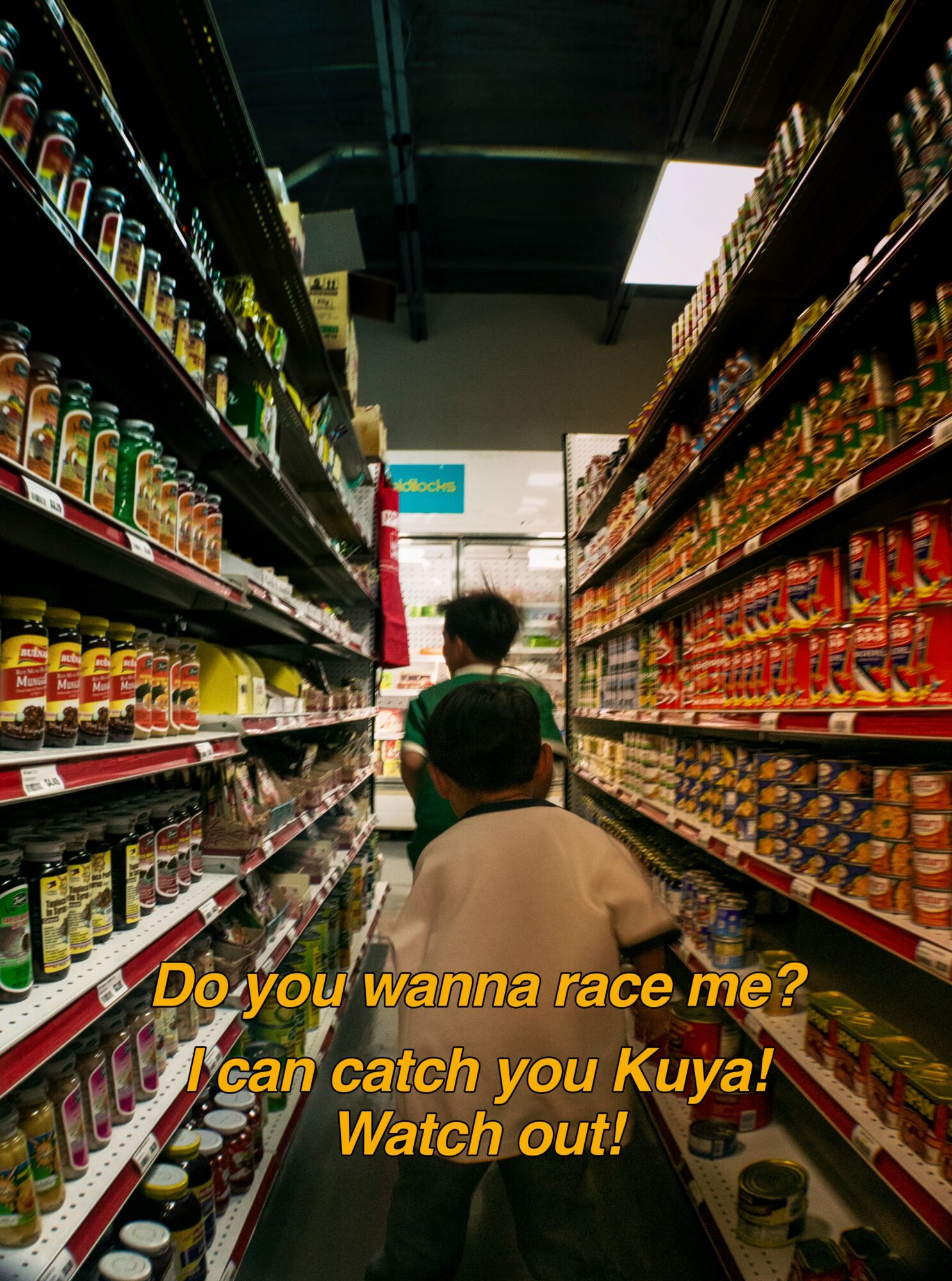 Two people in a grocery store aisle with shelves of jars and cans, one person facing away, the other partially visible, with yellow text overlay.