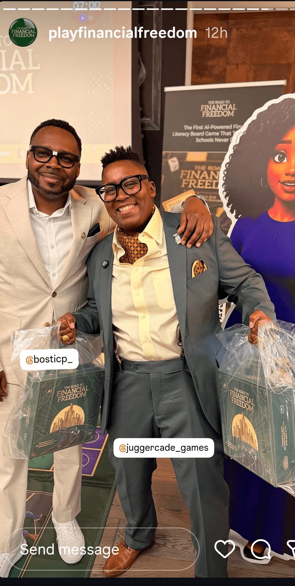 Two men smiling and standing together at an event, holding gift bags, with a woman in the background. Bright indoor setting.