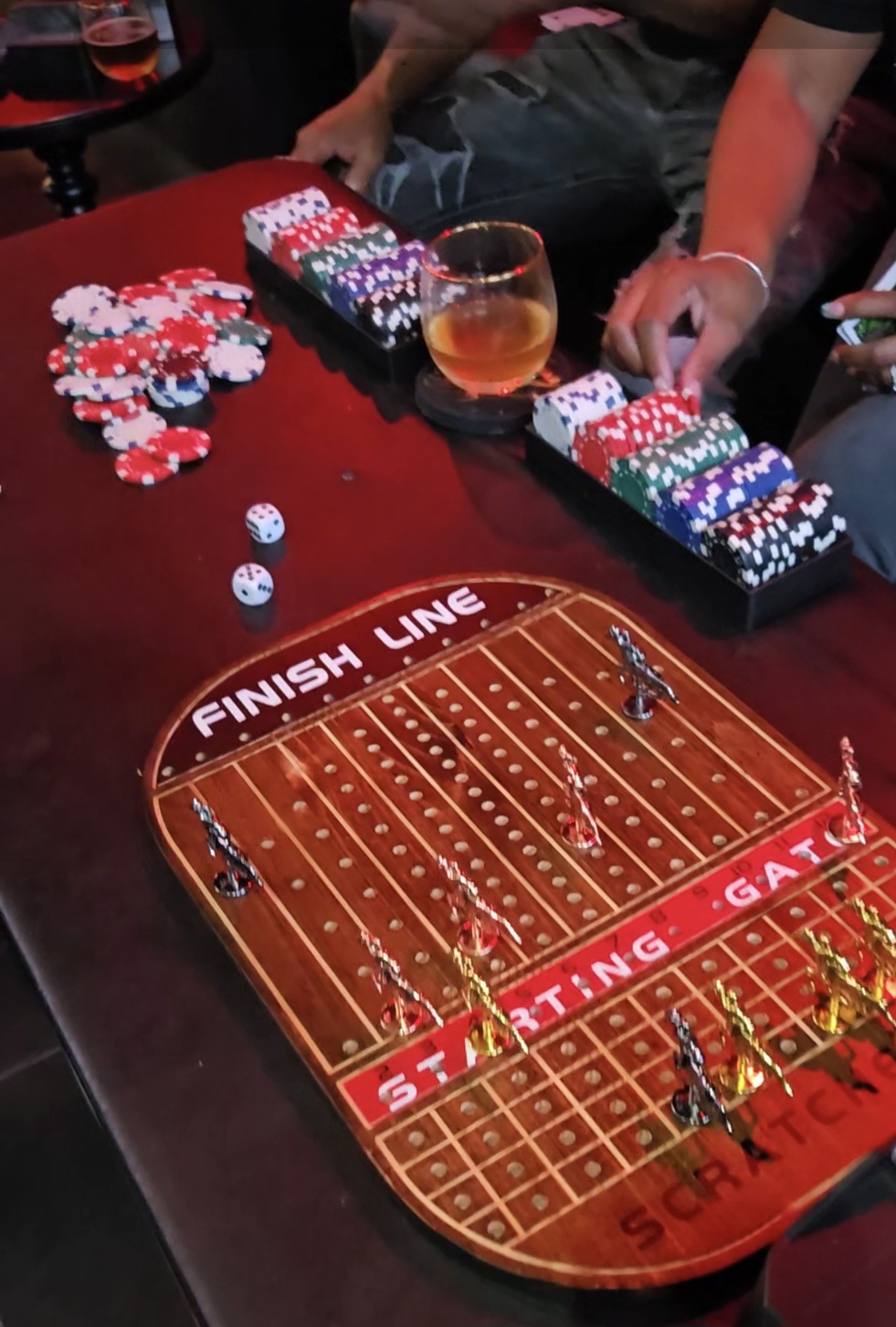 People playing a game with poker chips and dice on a table, with a hockey-themed game board in the foreground.