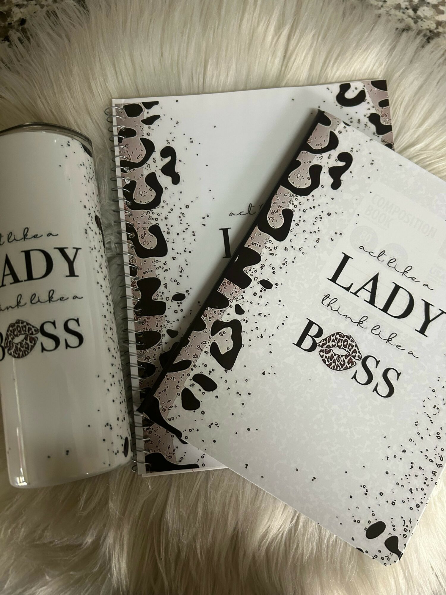 Three notebooks with black and white designs and text, placed on a soft, white surface.