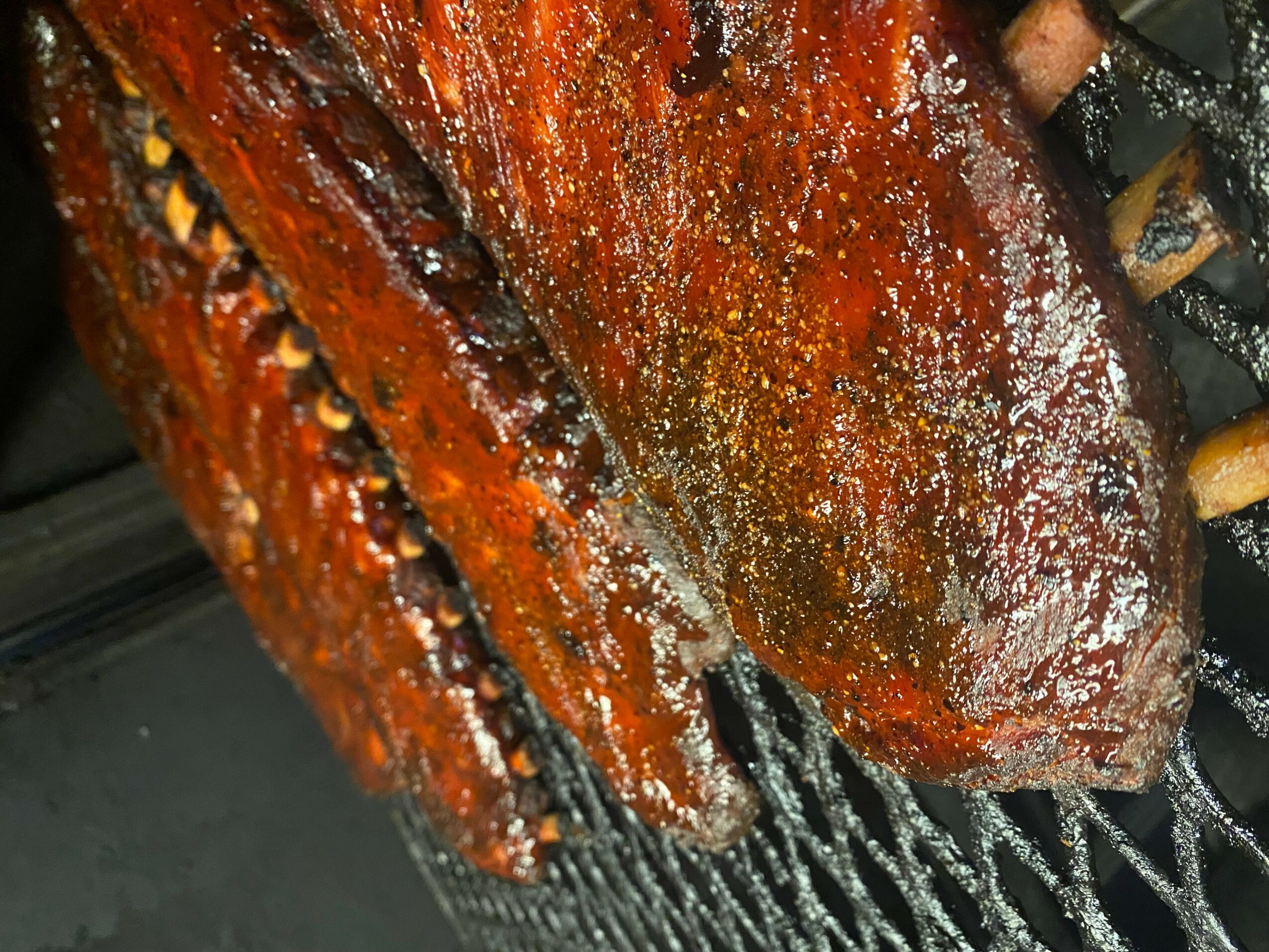Close-up of a grilled piece of meat with a charred surface and grill marks, resting on a grill rack.