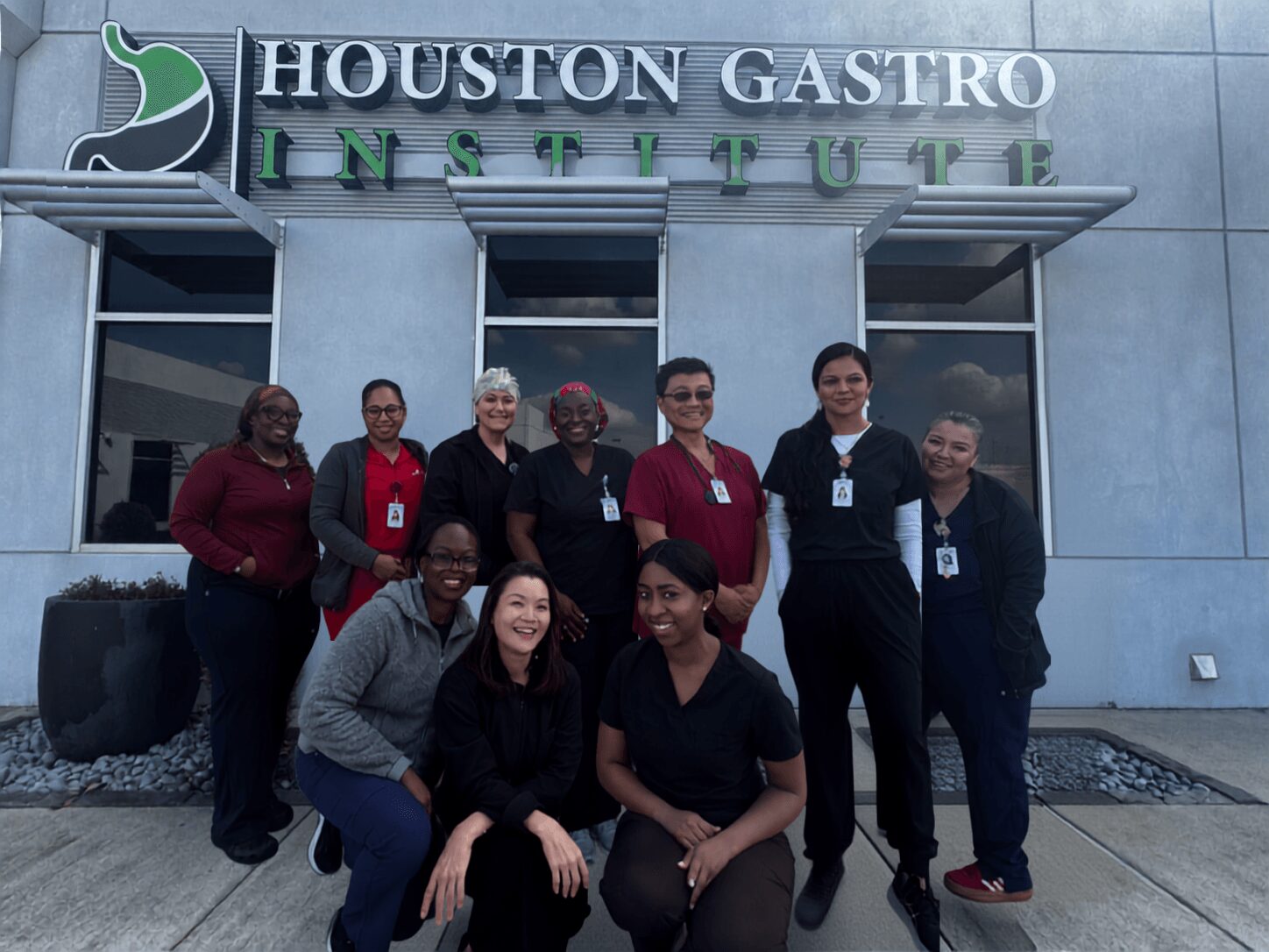 Group of nine people standing outside Houston Gastro Institute building, smiling, with sign above entrance.