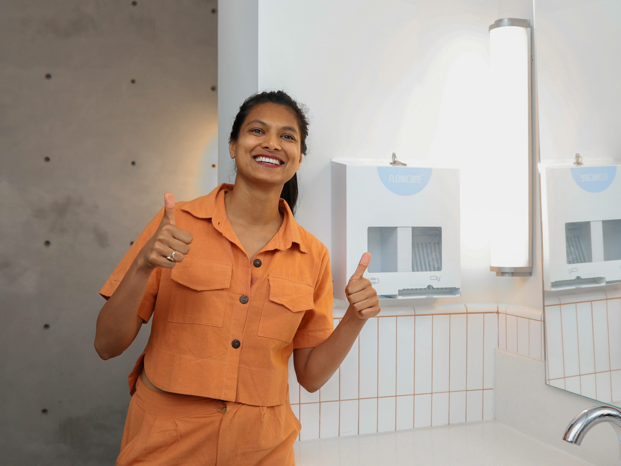 Smiling woman giving a thumbs-up in a modern room with white walls and equipment.
