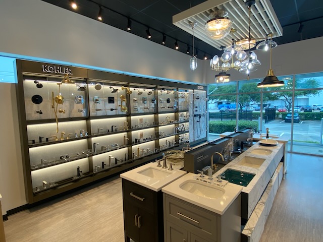 Modern coffee shop interior with display shelves, a long counter with sinks, and large windows showing outside view.