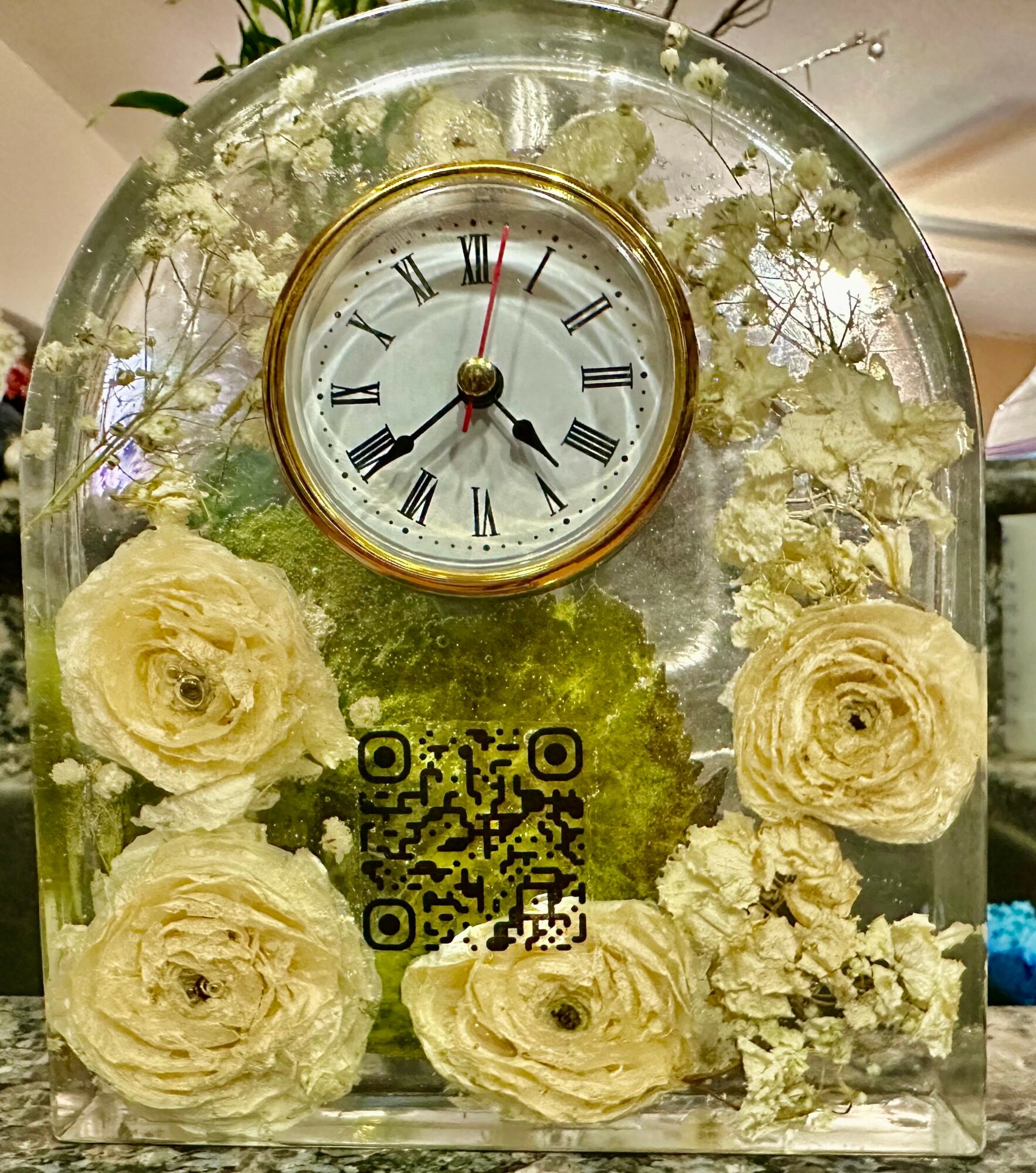 A decorative clock with Roman numerals and a floral design background, featuring white roses and greenery, with a QR code below.
