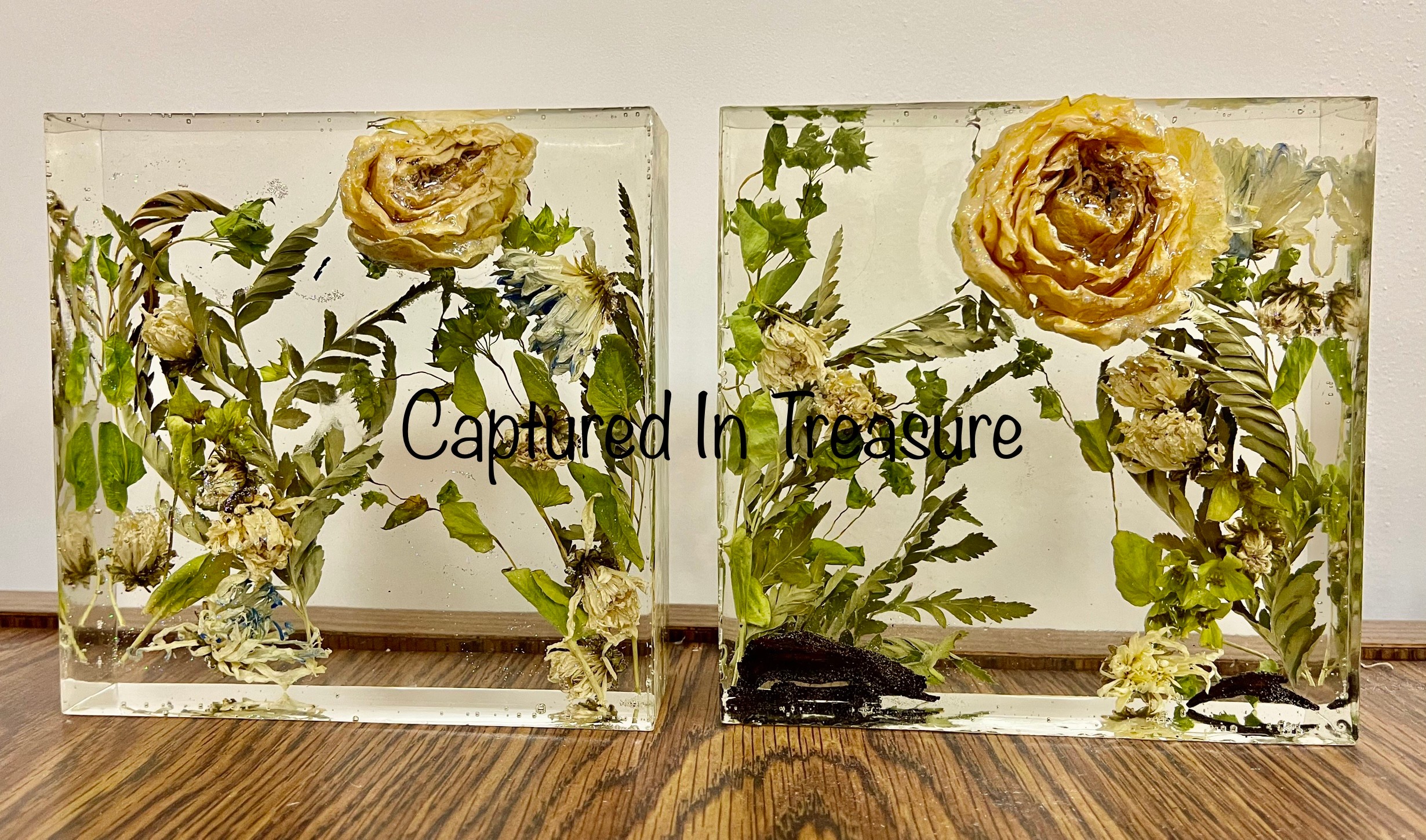 Two glass containers with yellow flowers and green foliage, placed on a wooden surface, with text overlay reading 'Captured In Treasure'.