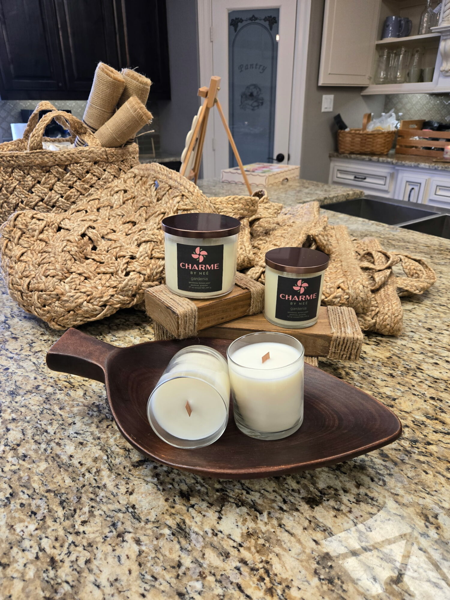 Decorative candles on a wooden tray with woven baskets and kitchen cabinets in the background.