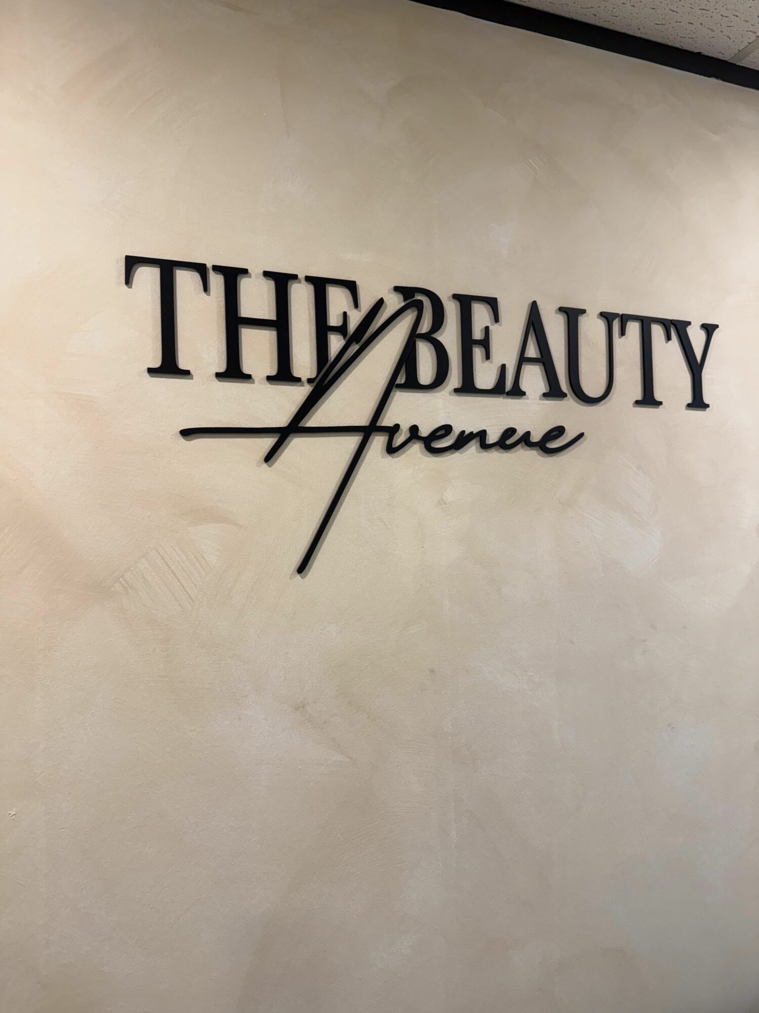 Wall sign reads 'THE BEAUTY avenue' with stylized text, on a plain wall.