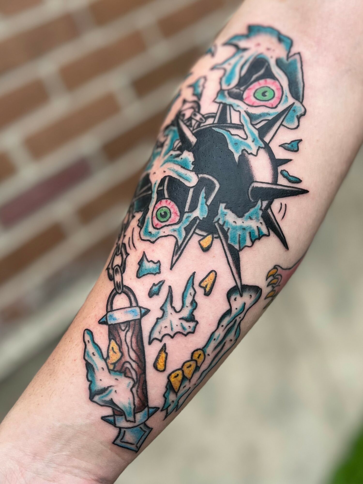 Tattoo of a stylized, abstract creature with multiple eyes, sharp features, and dripping elements on a person's arm.
