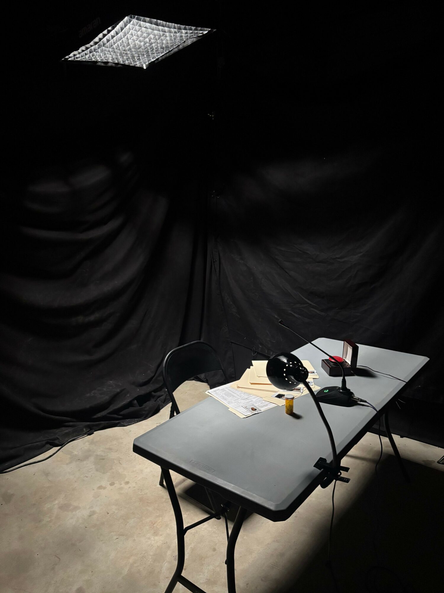 A small table with electronic devices and cables, next to a person wearing dark clothing, on a concrete floor.