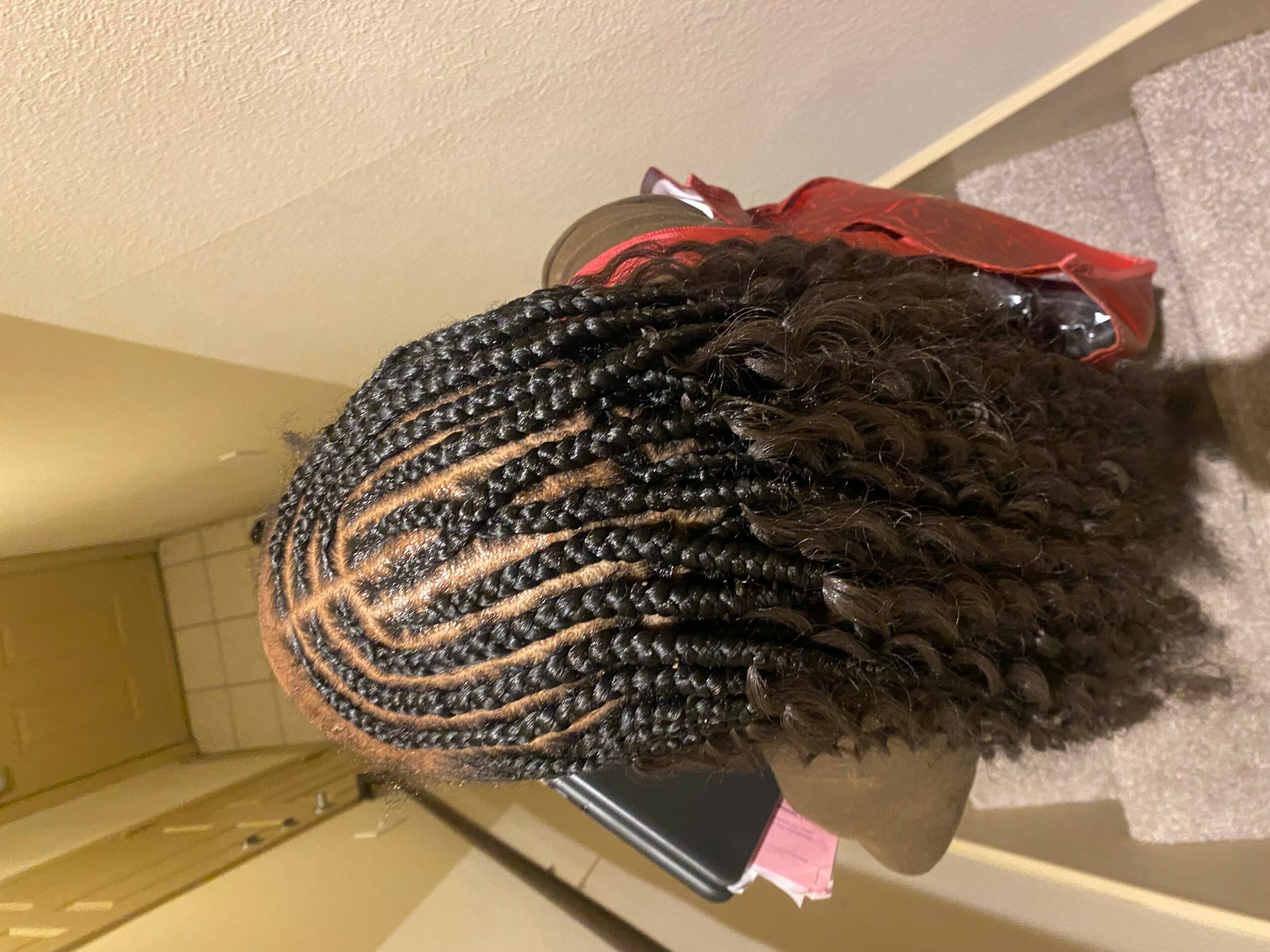 Top view of a person with braided hairstyle, showing intricate braids and curly hair at the ends.