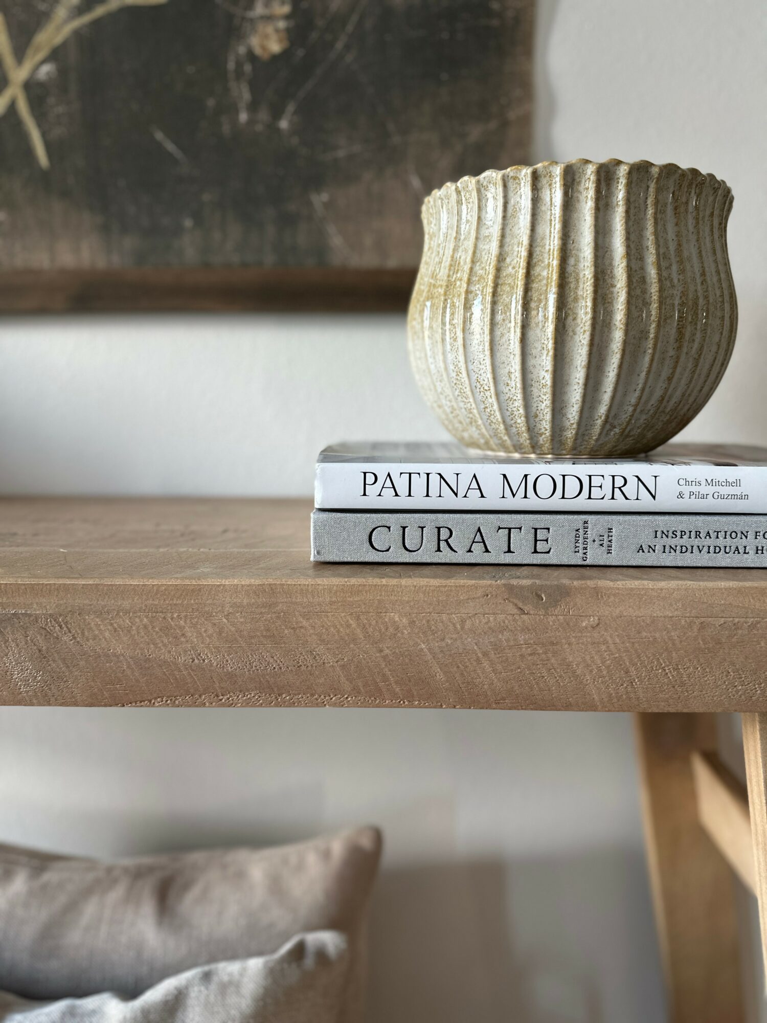 A textured, ribbed ceramic bowl sits on two stacked books on a wooden surface.
