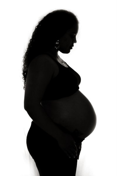 Silhouette of a pregnant woman in profile against a white background, with her hand on her belly.