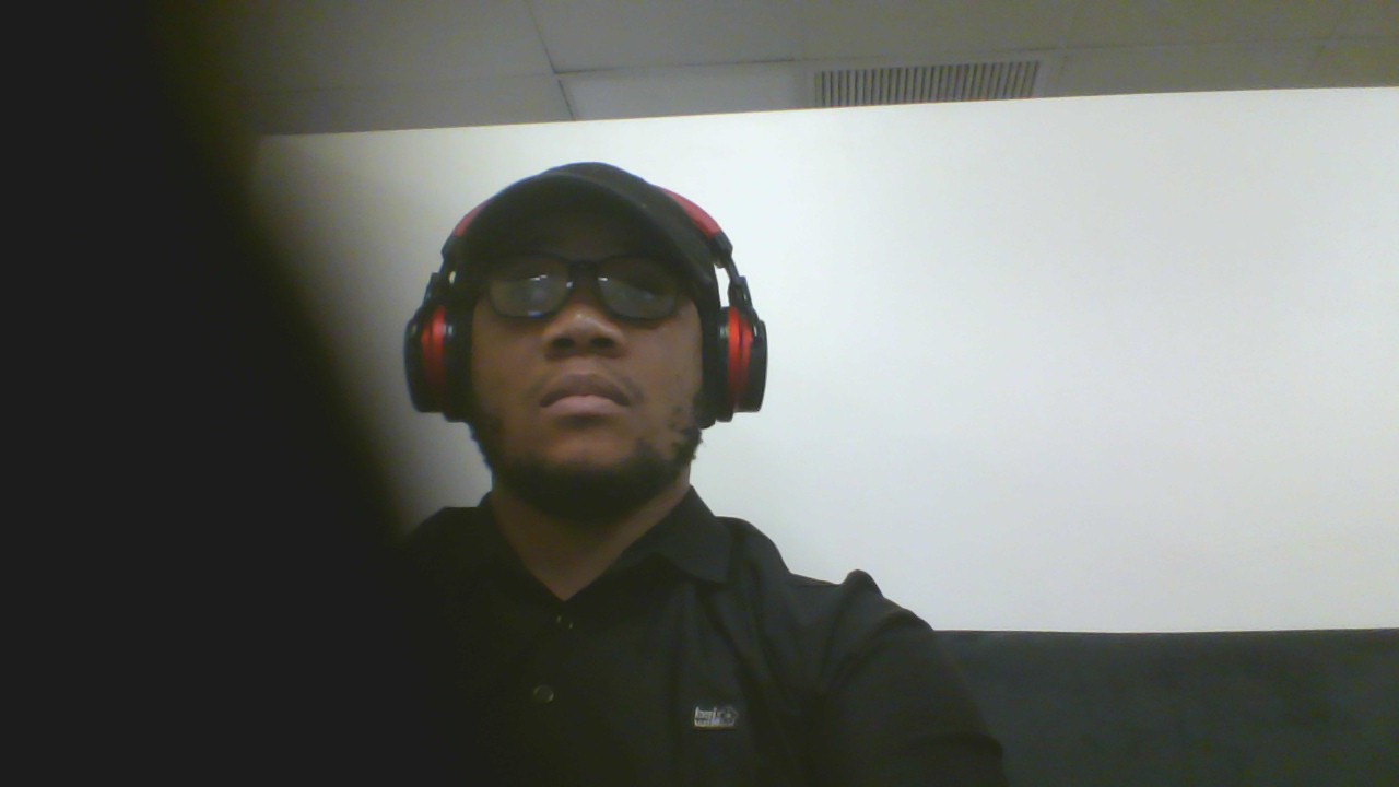 Person wearing headphones and glasses, looking at the camera, with a white background.