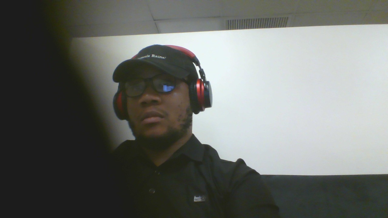 Person wearing headphones and sunglasses, facing camera, with a white background.