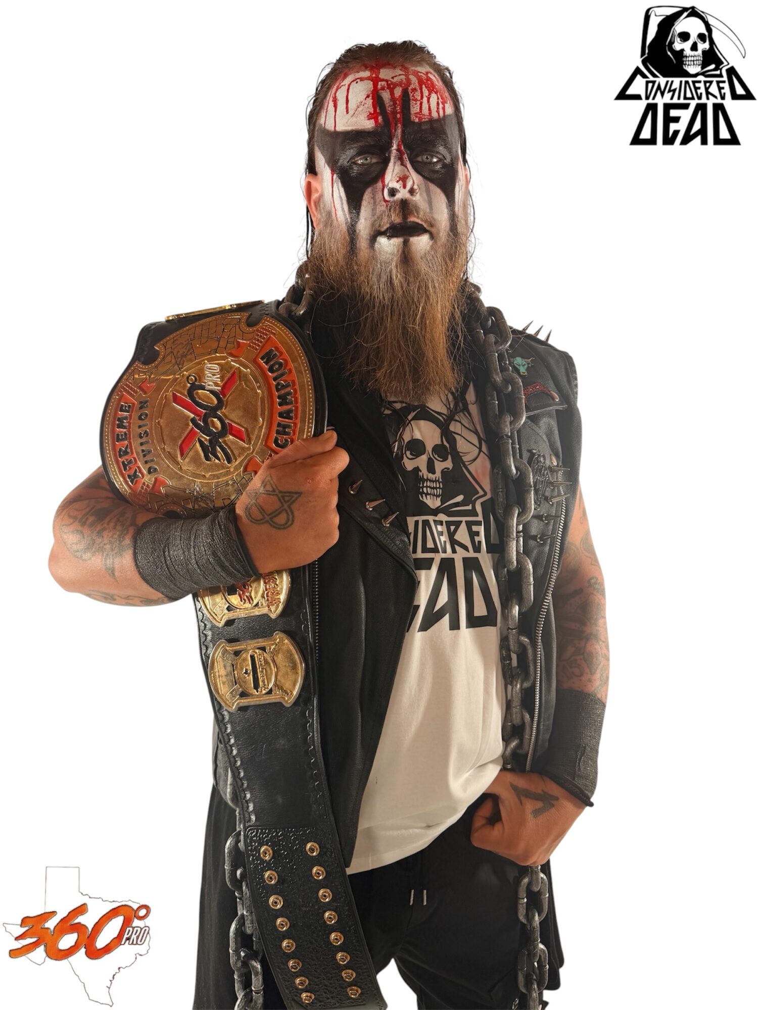 Person with face paint, long beard, wearing a vest, holding a championship belt, and wearing skull-themed clothing.
