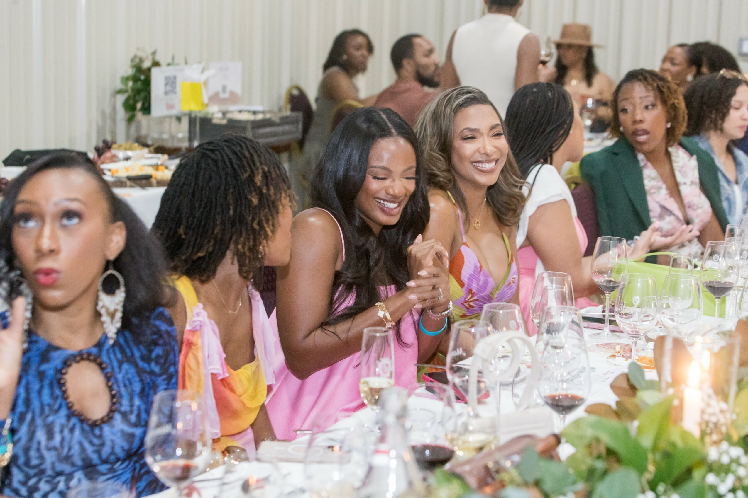 Group of women sitting at a decorated table, smiling and enjoying a celebration, with food and drinks present.