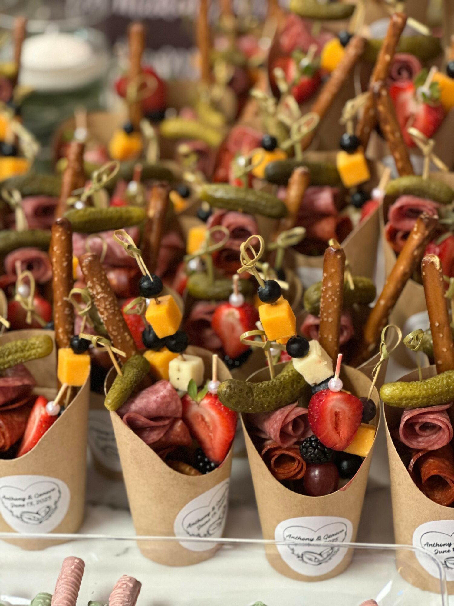 Small cones filled with fruit and pretzels, decorated with small yellow and black items, arranged in rows.