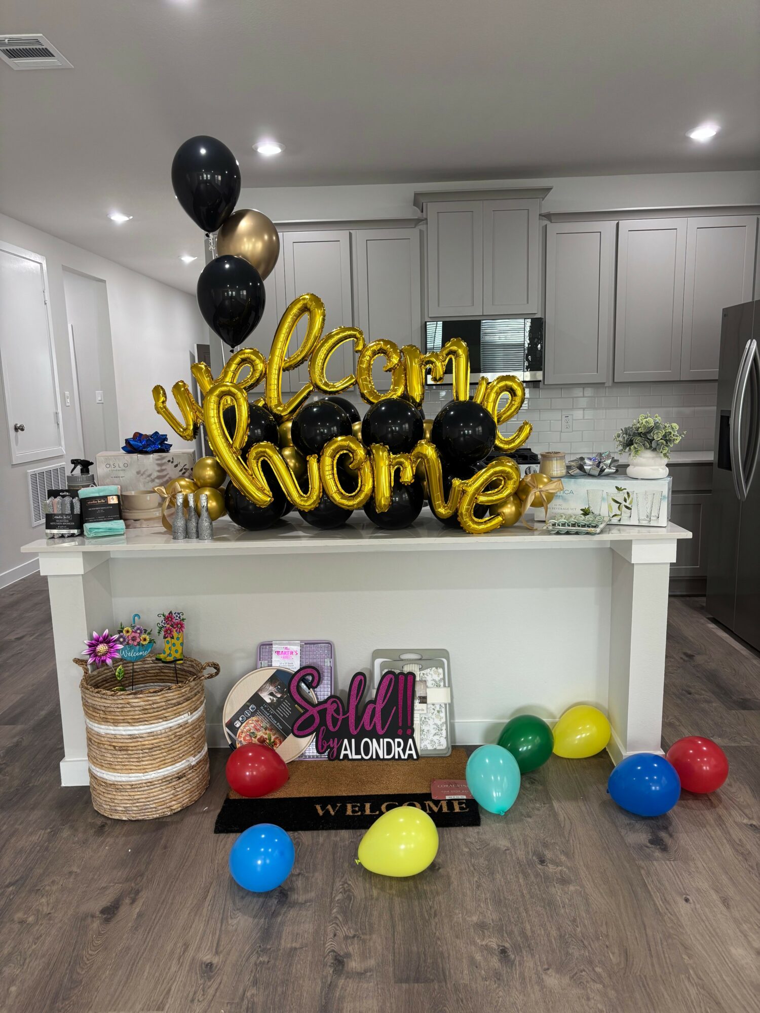Party decorations with balloons, a cake, and a sign reading 'Happy Birthday' on a white table in a room.