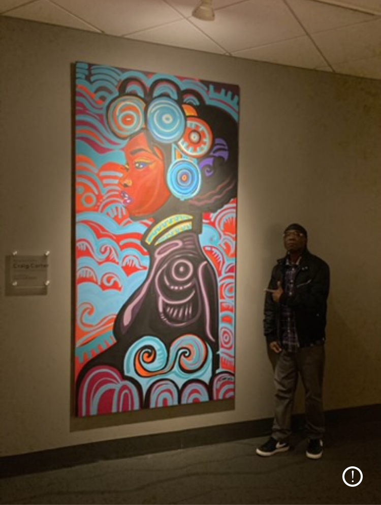 Person standing next to colorful abstract artwork featuring a face, waves, and swirling patterns on a wall.