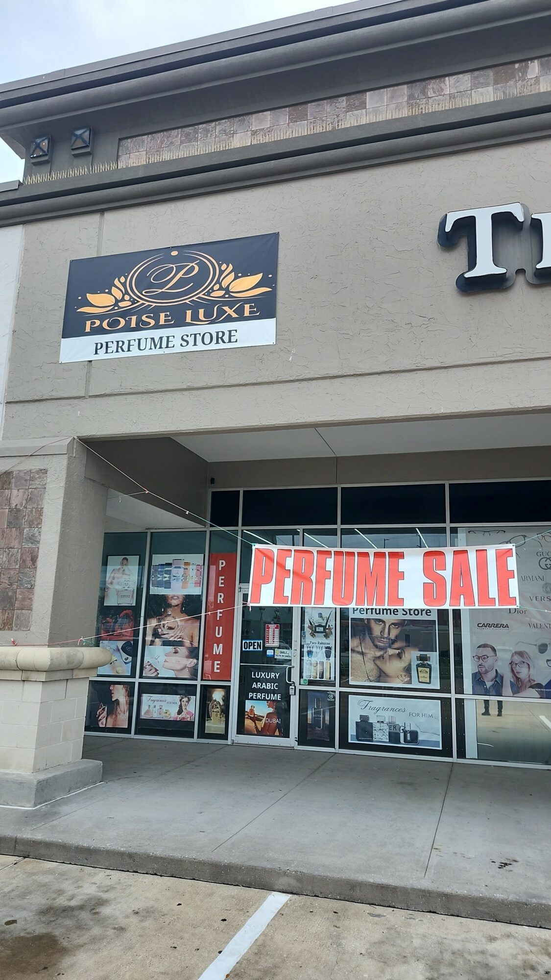 Storefront with a sign for Boise Luxe Perfume Store and a large red and white sign for perfume sale, window displays visible.