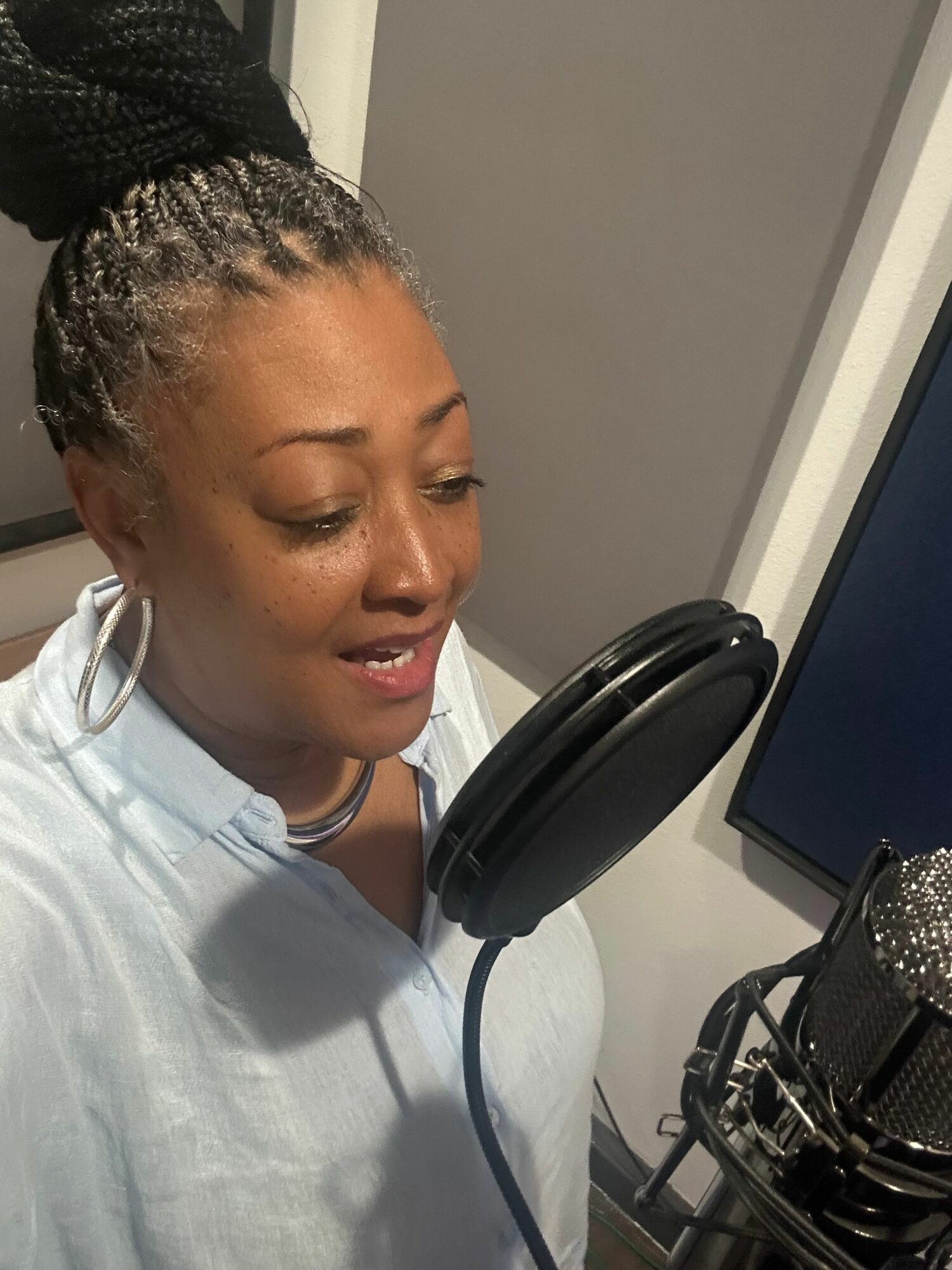 Woman lying in a medical or recording studio with headphones, eyes closed, and a microphone nearby.