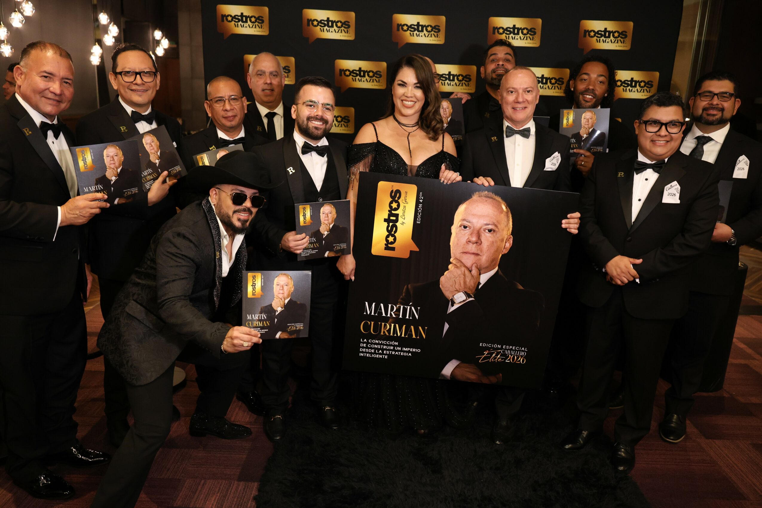 Group of people in formal attire holding posters at an event, with a backdrop displaying the Rostro logo.