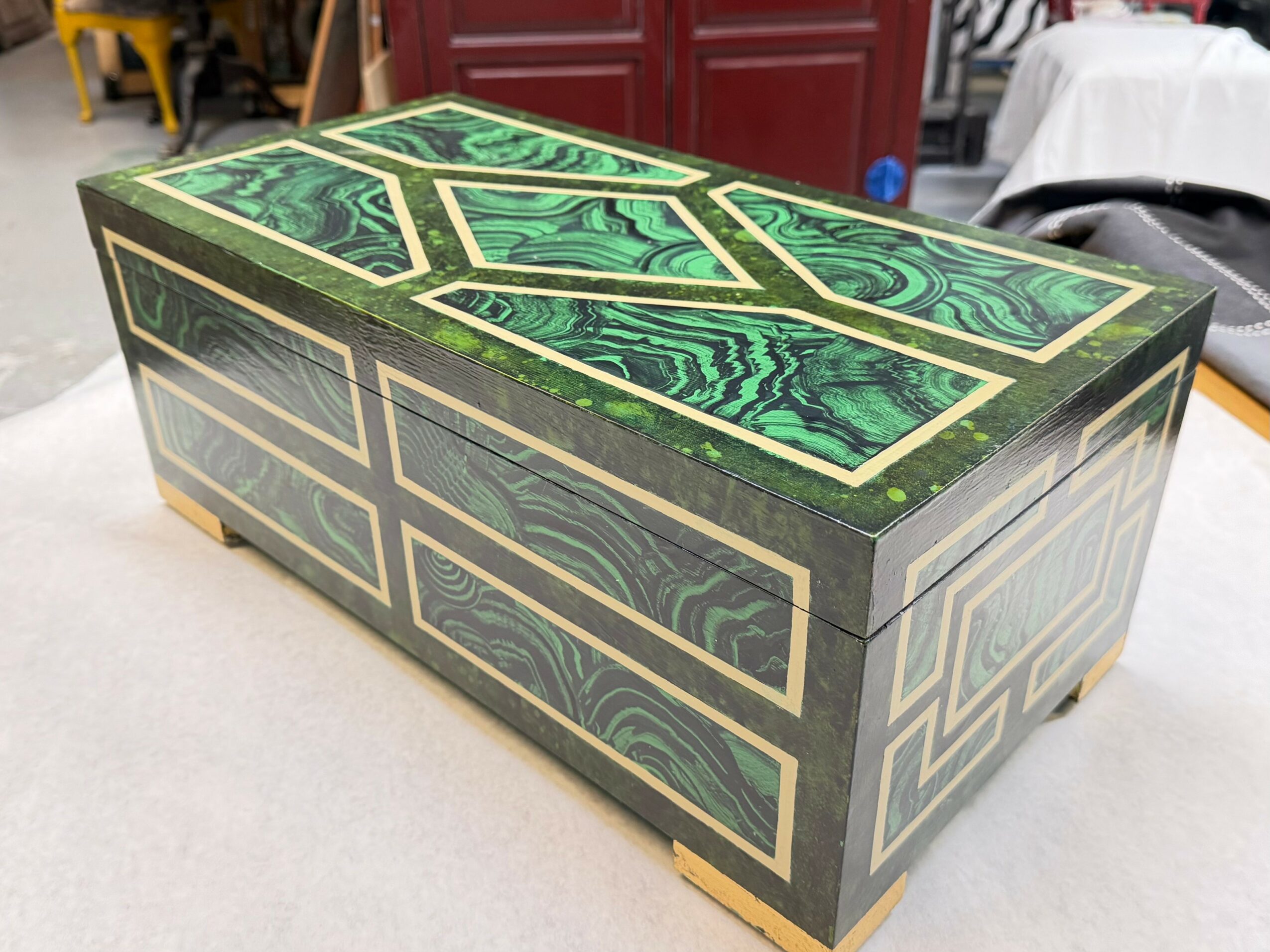 Rectangular box with green and black marbled pattern and gold accents, placed on a table.