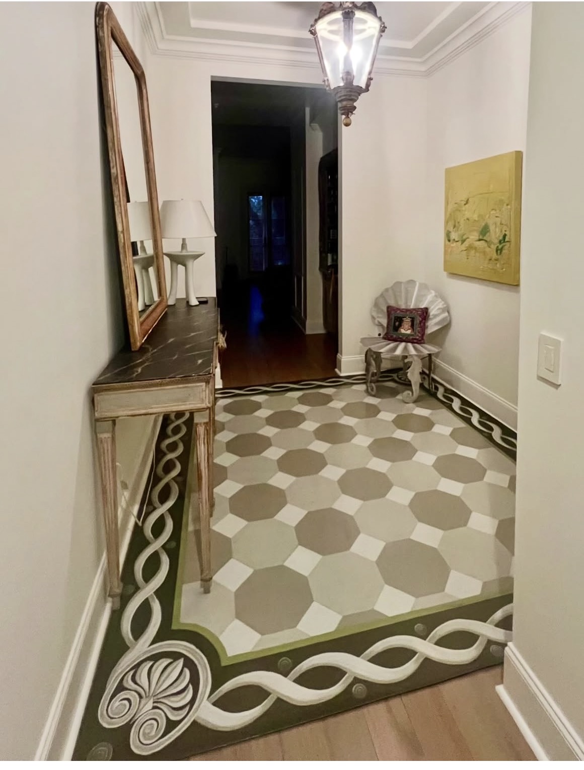 Entryway with patterned tile floor, mirror, small chair with decorative pillow, and artwork on wall.