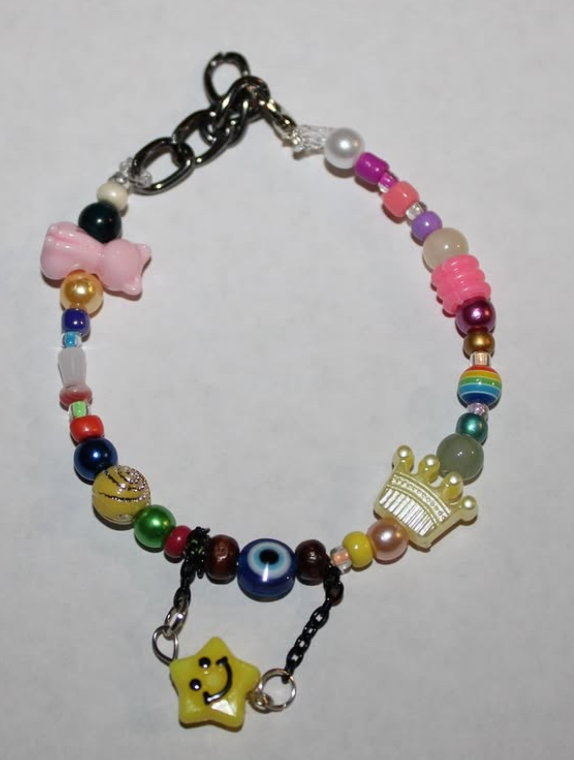Colorful beaded bracelet with a yellow star charm and a crown charm, featuring various beads and a chain link.