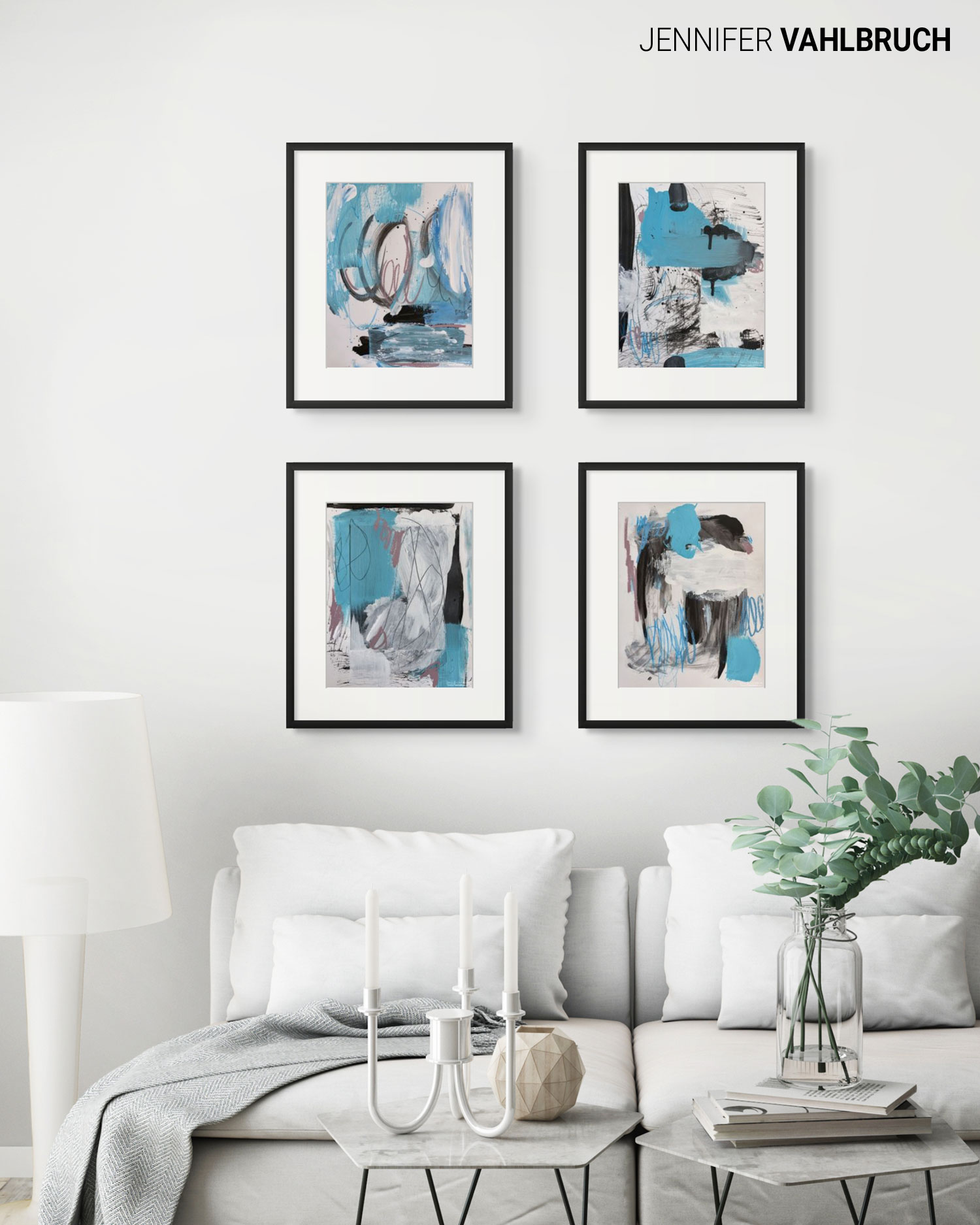 Four abstract paintings in black frames hang above a white sofa with cushions, a lamp, and a plant in a living room.