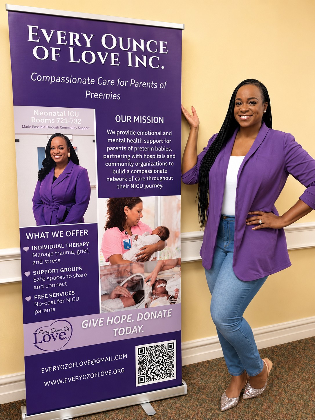 Woman in purple blazer and jeans standing next to a purple and white banner for Every Ounce of Love Inc., smiling with hands on hips.