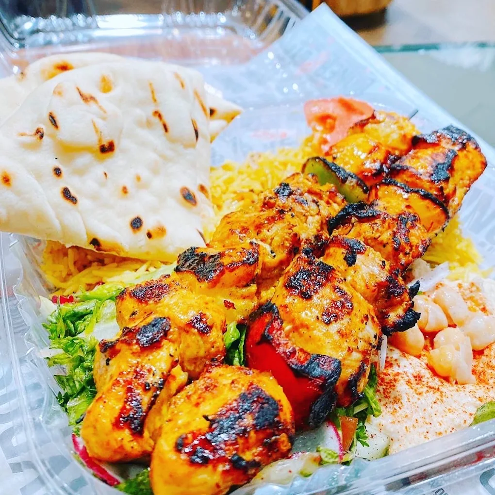 Skewered grilled chicken with vegetables, served with flatbread, rice, and shrimp on a tray.